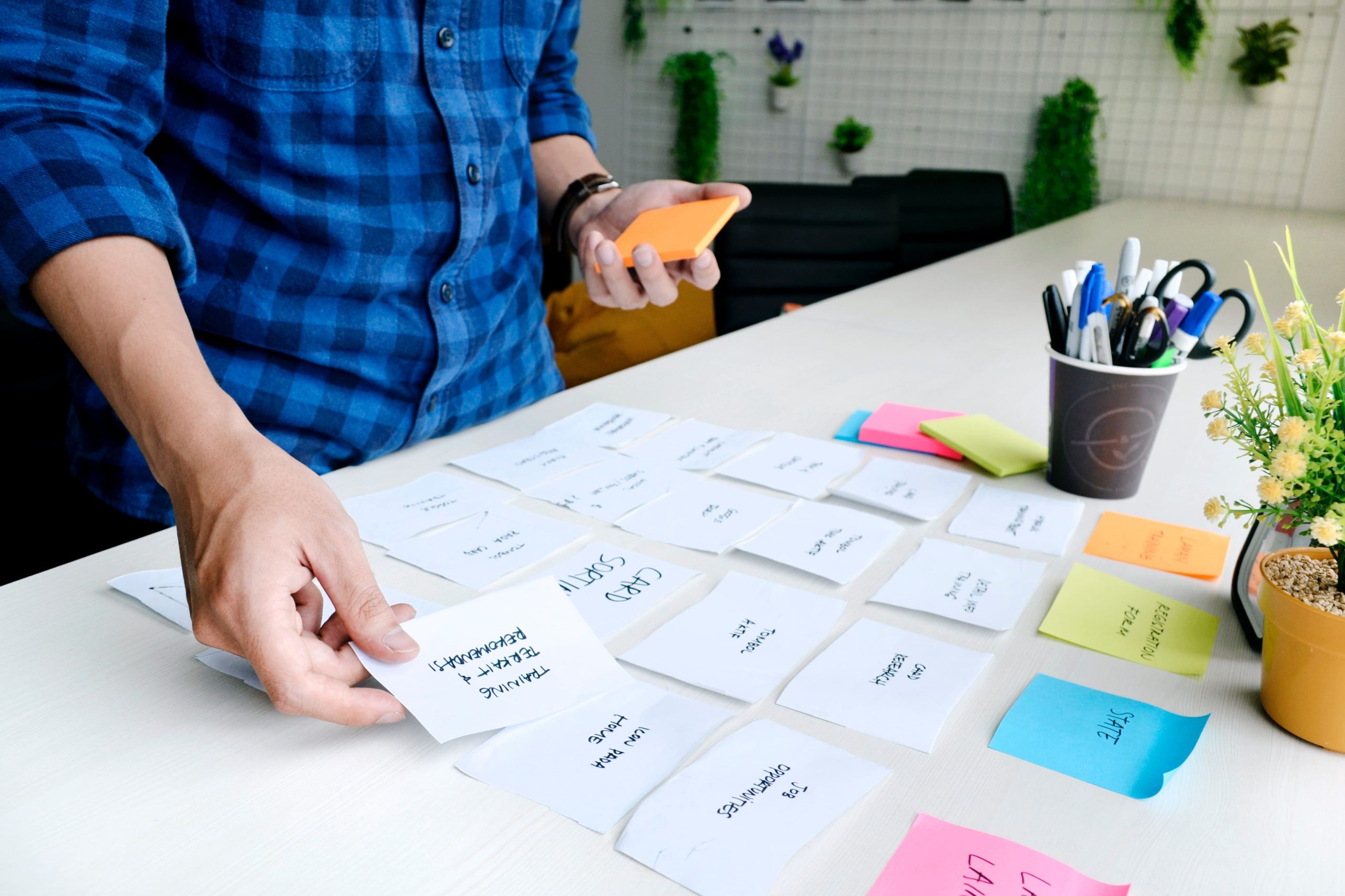 A person strategically placing sticky notes on a table, symbolizing the Agile methodology and thoughtful assessment of options for effective decision-making.